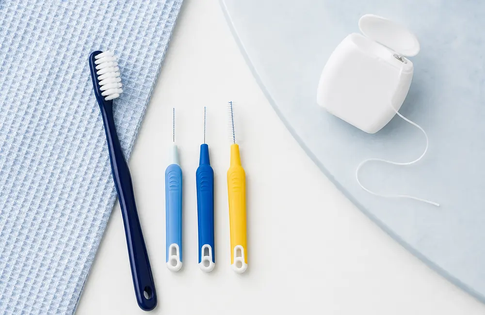 Soft toothbrush, interdental brushes and dental floss on a light surface
