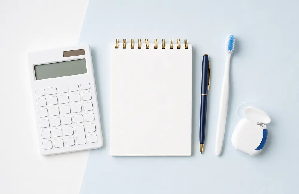 Calculator and a blank notepad beside a toothbrush and dental floss